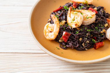 Sarımsaklı ve karidesli kızarmış siyah spagetti.