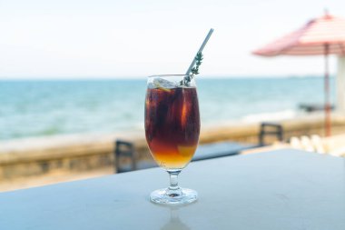 Okyanus arkaplanlı buzlu americano kahve şeftalisi.