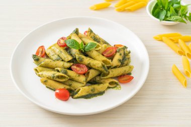 Pesto soslu ve domatesli makarna. Vejetaryen ve vejetaryen yemek tarzı.