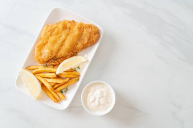 balık ve patates kızartması - kızarmış balık fileto patates cipsi ve limonlu beyaz tabak