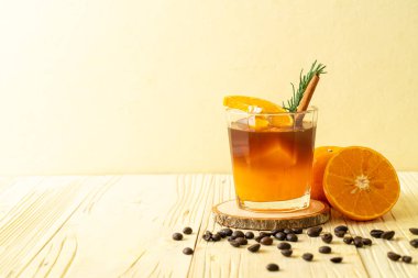 Bir bardak buzlu americano sade kahve ve biberiye ve tarçınla süslenmiş portakal ve limon suyu.