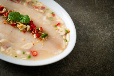 Beyaz tabakta baharatlı limon soslu balık.