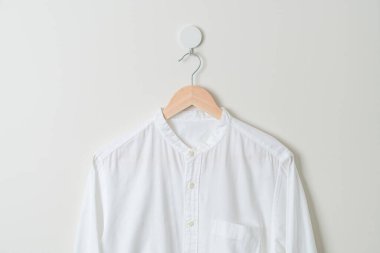 Duvarında ahşap askı olan beyaz gömlek asılı.