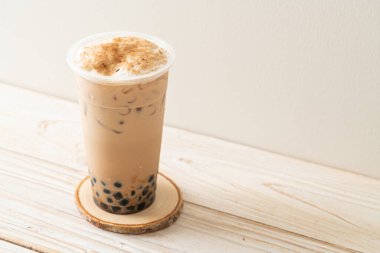 Tahta masada yanmış köpüklü ve peynirli Tayvan sütü çayı.