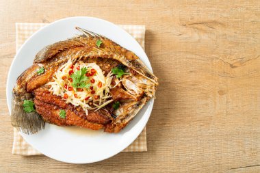 Balık soslu kızarmış deniz levreği balığı ve tabakta baharatlı salata.