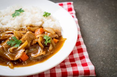 Dilimlenmiş domuz eti, havuç ve soğanlı Japon körili pilavı. Asya usulü.