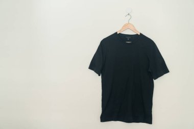 black t-shirt hanging with wood hanger on wall