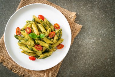 Pesto soslu ve domatesli makarna. Vejetaryen ve vejetaryen yemek tarzı.