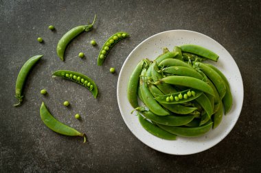 Taze yeşil bezelyeler beyaz tabakta