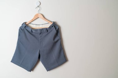 Kısa pantolon duvarda ahşap bir askıyla asılı.
