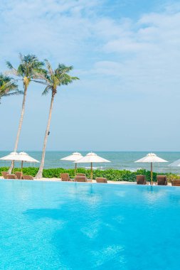 Okyanus geçmişi olan yüzme havuzunun etrafında havuzu olan şemsiyeler - tatil ve tatil kavramı