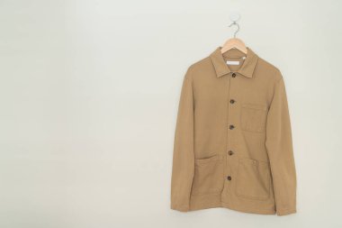 beige suit hanging with wood hanger on wall