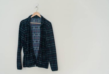 black jacket hanging with wood hanger on wall