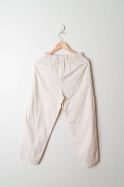 Pantolon ya da uzun pantolon duvarda ahşap askıyla asılı.