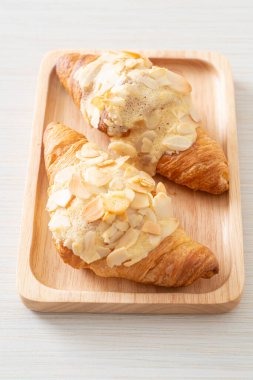 Kremalı kruvasan ve ahşap tabakta badem.