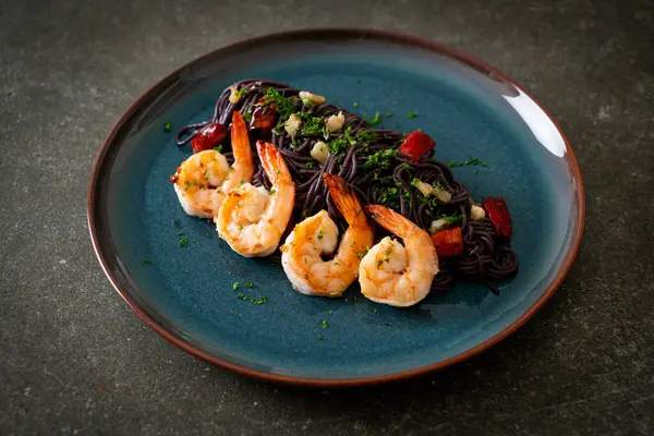 Sarımsaklı ve karidesli kızarmış siyah spagetti.