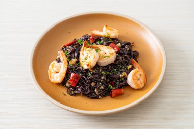 Sarımsaklı ve karidesli kızarmış siyah spagetti.