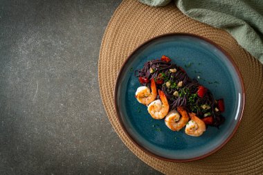 Sarımsaklı ve karidesli kızarmış siyah spagetti.