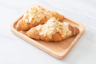 Kremalı kruvasan ve ahşap tabakta badem.