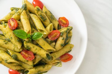 Pesto soslu ve domatesli makarna. Vejetaryen ve vejetaryen yemek tarzı.