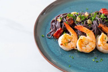 Sarımsaklı ve karidesli kızarmış siyah spagetti.