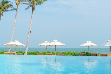 Okyanus geçmişi olan yüzme havuzunun etrafında havuzu olan şemsiyeler - tatil ve tatil kavramı