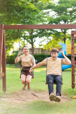 Asian couple love play on the swing in kids playground