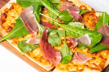 Parma jambonlu turta ve tahta üzerinde roket pizzası.