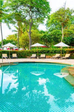 Şemsiye ve sandalye tatil ve tatil için dinlenme yeri otelinde yüzme havuzunda günbatımında veya gün doğumunda okyanus kıyısında