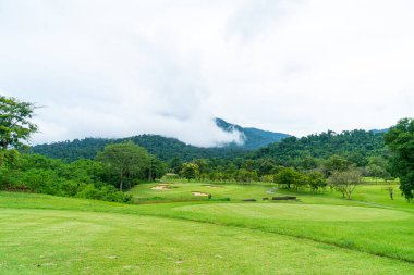 Green and Sand bunkers on Golf course with mountain hill background