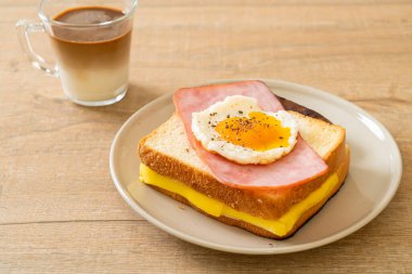 Ev yapımı ekmek üzerine kızarmış peynir jambon ve kızarmış yumurta ile domuz sosisi ve kahvaltıda kahve.