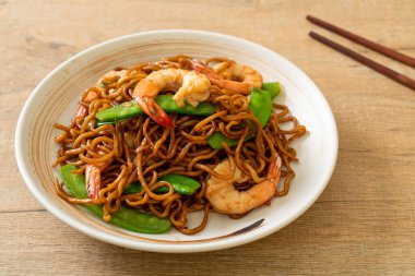 Kızarmış yakisoba eriştesi, yeşil bezelye ve karides, Asya usulü.