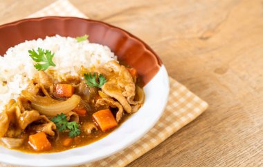 Dilimlenmiş domuz eti, havuç ve soğanlı Japon körili pilavı. Asya usulü.