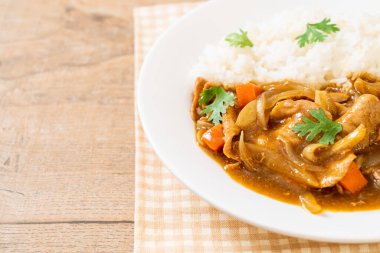 Dilimlenmiş domuz eti, havuç ve soğanlı Japon körili pilavı. Asya usulü.