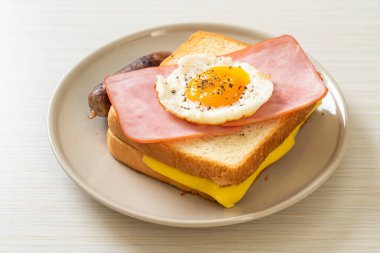 homemade bread toasted cheese topped ham and fried egg with pork sausage for breakfast clipart