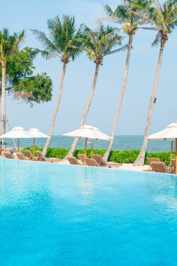 Okyanus geçmişi olan yüzme havuzunun etrafında havuzu olan şemsiyeler - tatil ve tatil kavramı