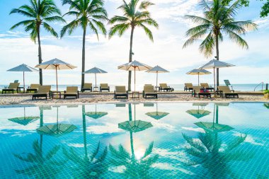Otelde ve tatil beldesinde yüzme havuzunda güzel şemsiye ve sandalye - tatil kavramı