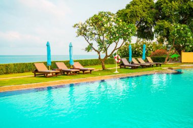 Sandalye havuzu ve şemsiyeyle okyanus arka planında yüzme havuzu