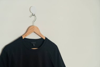 black t-shirt hanging with wood hanger on wall