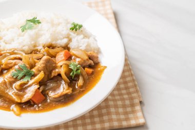 Dilimlenmiş domuz eti, havuç ve soğanlı Japon körili pilavı. Asya usulü.
