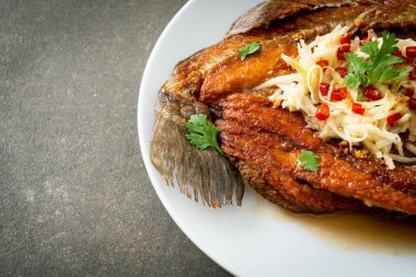 Balık soslu kızarmış deniz levreği balığı ve tabakta baharatlı salata.