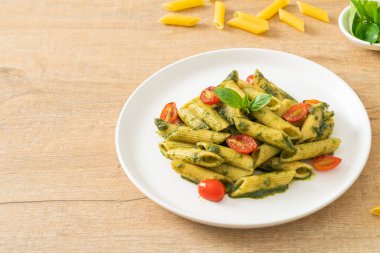 Pesto soslu ve domatesli makarna. Vejetaryen ve vejetaryen yemek tarzı.
