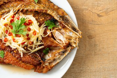 Balık soslu kızarmış deniz levreği balığı ve tabakta baharatlı salata.