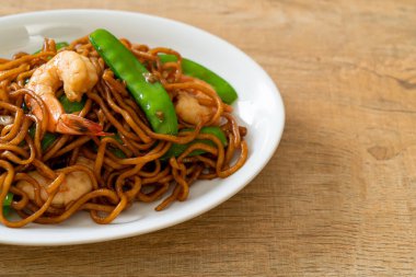 Kızarmış yakisoba eriştesi, yeşil bezelye ve karides, Asya usulü.