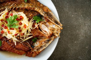 Balık soslu kızarmış deniz levreği balığı ve tabakta baharatlı salata.