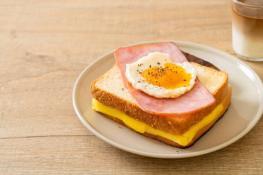 Ev yapımı ekmek üzerine kızarmış peynir jambon ve kızarmış yumurta ile domuz sosisi ve kahvaltıda kahve.