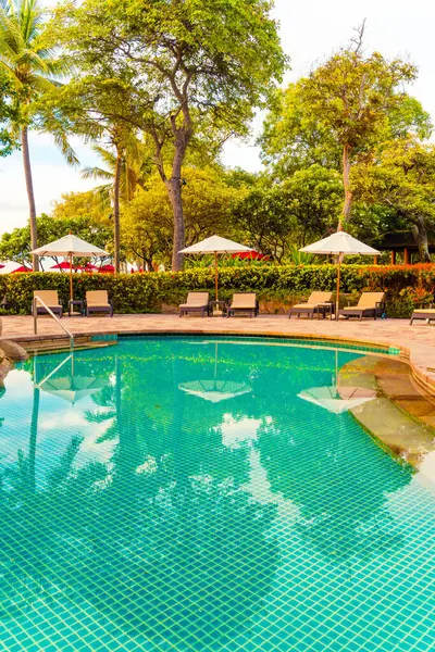 Şemsiye ve sandalye tatil ve tatil için dinlenme yeri otelinde yüzme havuzunda günbatımında veya gün doğumunda okyanus kıyısında