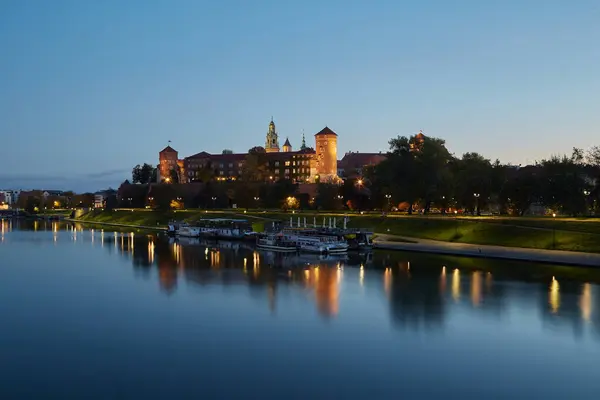 クラクフ ポーランド 2022 ヴィスラ川の岸と浮遊船のレストランで夕方の青い時間に歴史的なワイエル城 ストック画像
