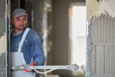 İnşaat için duvarların sıvanması. Pompalama ekipmanı kullanan bir malzeme katmanının uygulaması