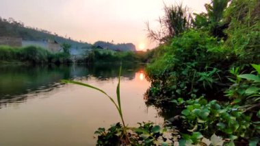 Batı Bandung, Endonezya 'daki güzel gölün çevresindeki yemyeşil bitki örtüsü, dağlar ve günbatımı.